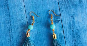 The Art of Adornment: How to Style Statement Earrings with Confidence and Class Stylish blue tassel earrings with gold accents displayed on a wooden surface.