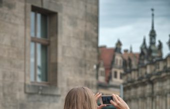 Pack Light, Travel Far: Real-World Tricks for Smarter Travel in 2025 woman in gray jacket taking photo using black dslr camera
