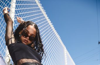 Style Survival: Real-Life Fashion Hacks to Battle Everyday Stains woman in black leather pants and top holding on white fence