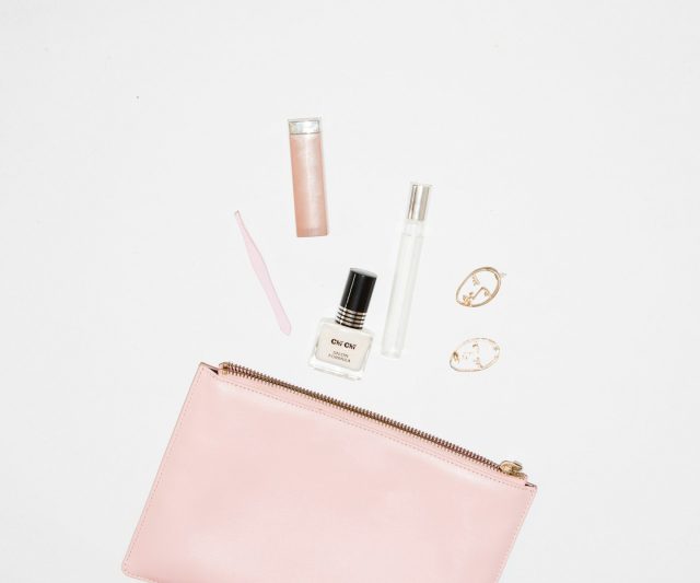 white nail polish bottle and pink leather zip pouch