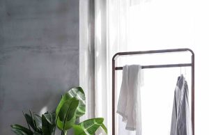 The Quiet Power of Essentials: Curating a Staple Accessories Collection That Lasts gray dress shirt hang on brown wooden rack in front of window with white curtain